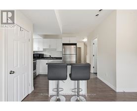 A kitchen with white cabinets and a black bar stool.