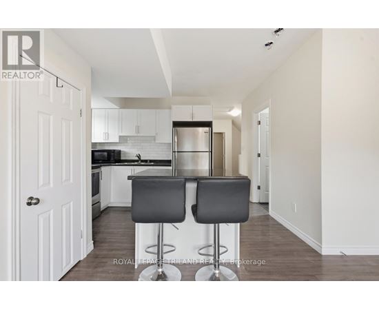 A kitchen with white cabinets and a black bar stool.