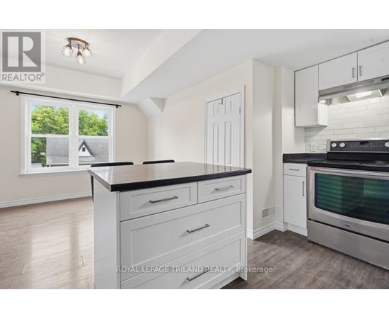 A kitchen with white cabinets and a black countertop.