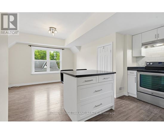 A kitchen with white cabinets and a black countertop.