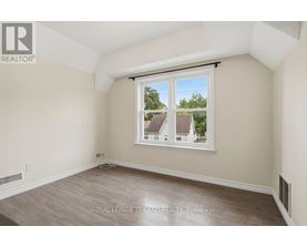 A room with a window showing a view of houses and trees outside.