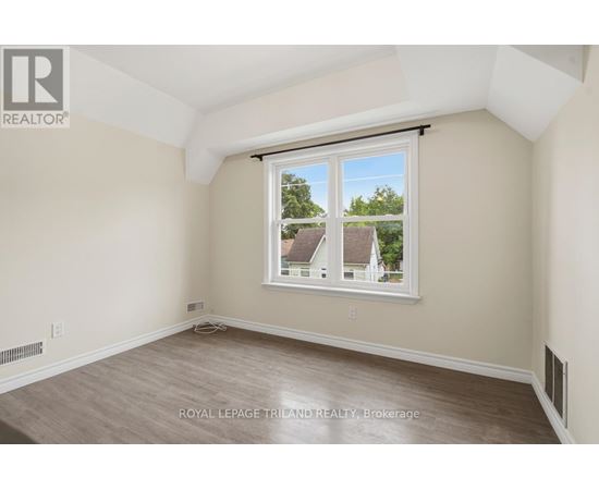 A room with a window showing a view of houses and trees outside.