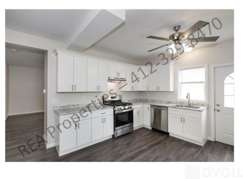 A modern kitchen with white cabinets and a wooden floor.