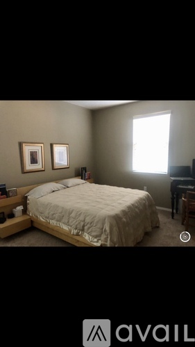 A bedroom with a bed, nightstand, and two pictures on the wall.