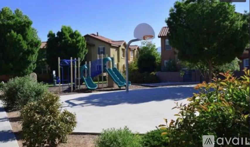 A playground with a blue slide and a green slide in the middle of a paved area.