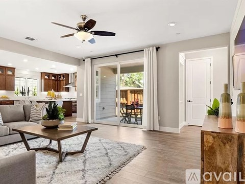 A living room with a ceiling fan and a coffee table in the center.