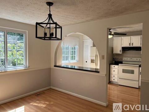 A kitchen with white cabinets and a window with blinds.