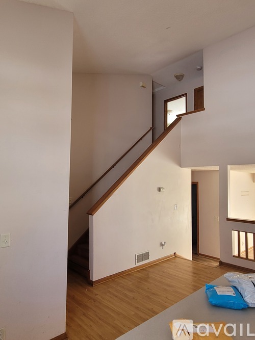 A living room with a staircase and a blue bag on the table.