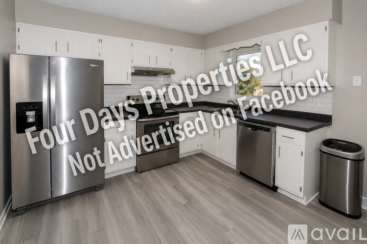 A kitchen with a stainless steel refrigerator and a trash can.