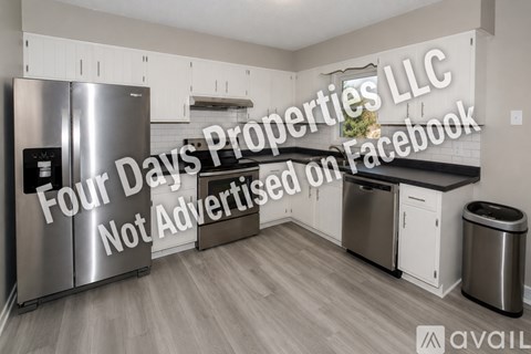A kitchen with a stainless steel refrigerator and a trash can.