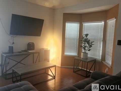 A living room with a television, a table with a plant, and a couch.