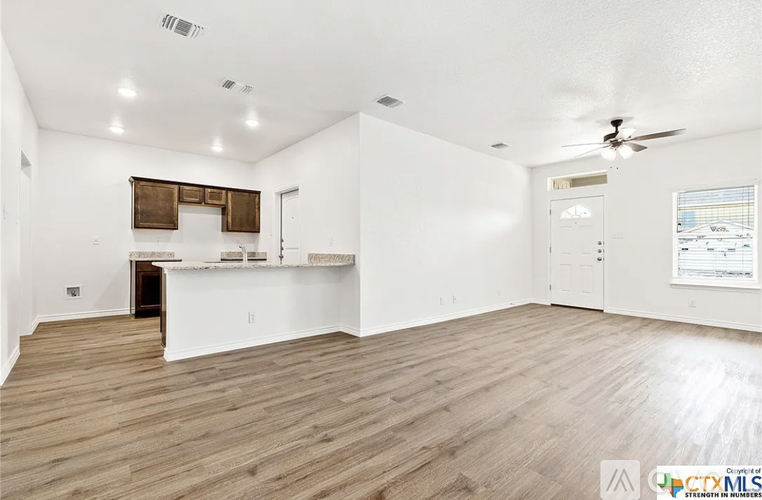 A spacious room with wooden flooring and a ceiling fan.