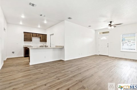 A spacious room with wooden flooring and a ceiling fan.