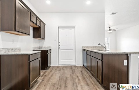 A kitchen with dark brown cabinets and a white door.