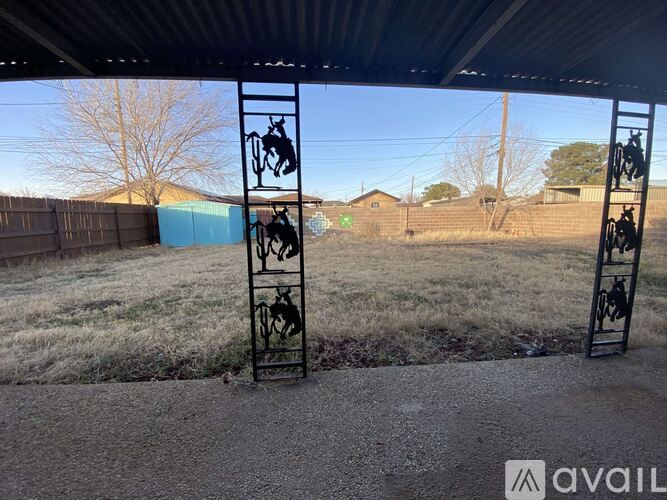 A metal gate with a horse and rider design is in the foreground of a grassy area.