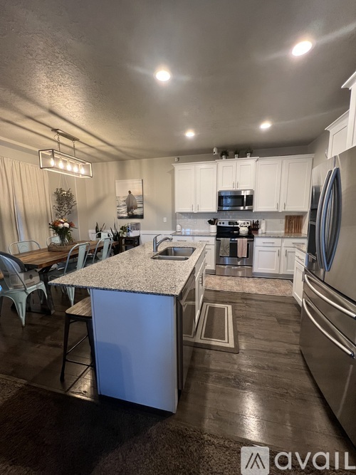 A kitchen with a large island in the middle and a dining table with chairs.