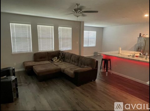 A living room with a brown couch and a ceiling fan.