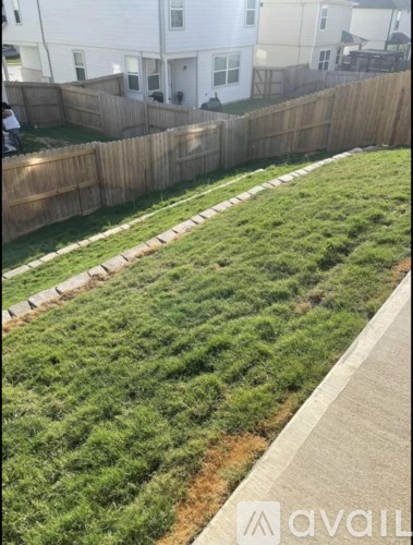 A grassy area with a wooden fence and a sidewalk.
