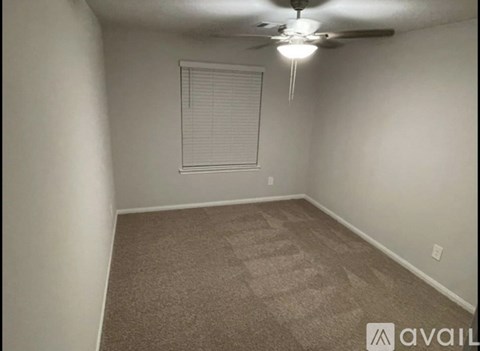 A room with a carpeted floor and a ceiling fan.