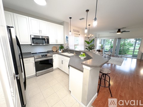 A kitchen with white cabinets and a black refrigerator.