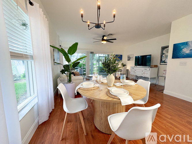 A dining room with a round table and white chairs.