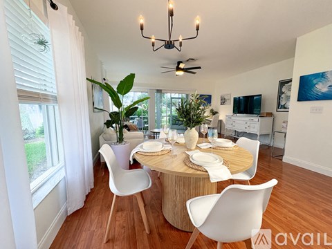 A dining room with a round table and white chairs.