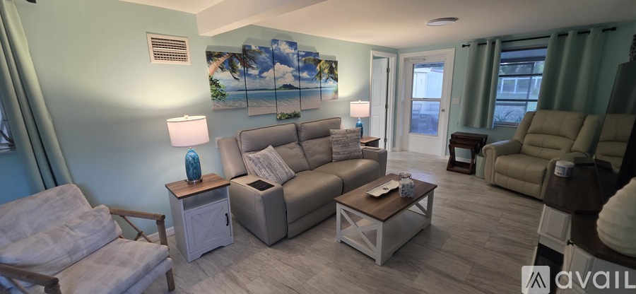 A living room with a sofa, armchair, and a painting on the wall.