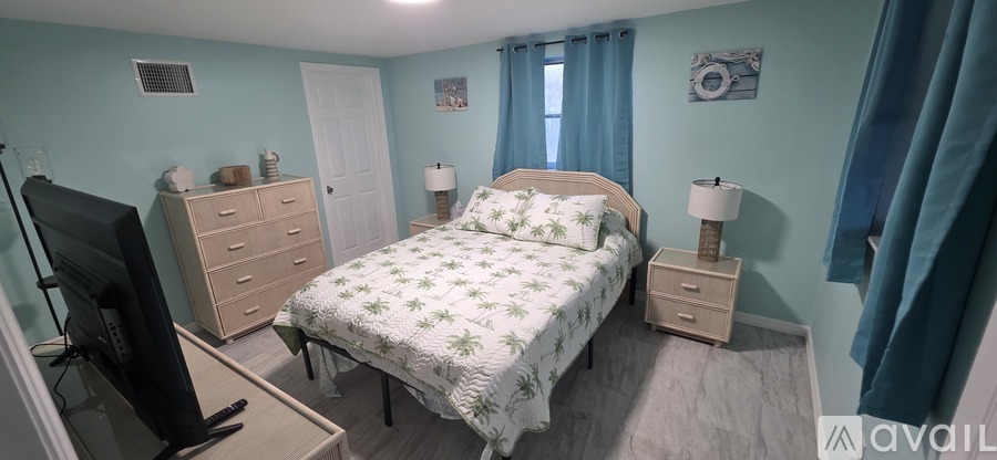 A bedroom with a bed, dresser, and television.