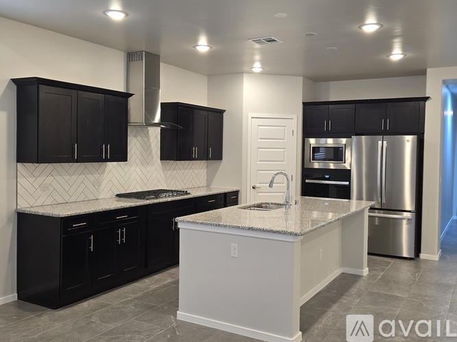 A kitchen with black cabinets and a white island.