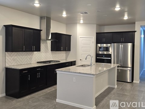 A kitchen with black cabinets and a white island.
