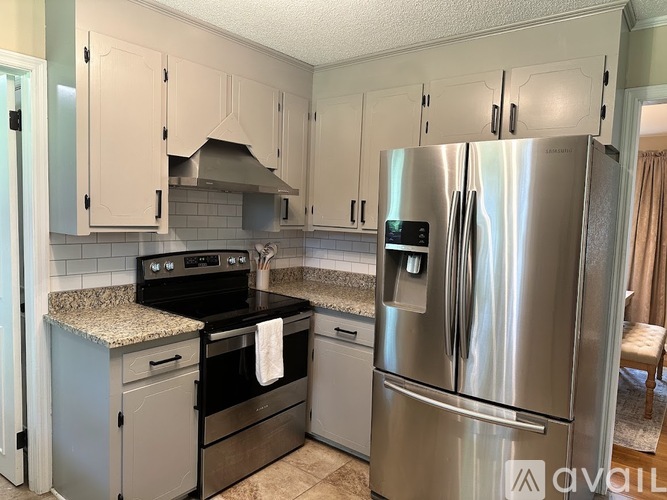 A kitchen with a stainless steel refrigerator and a black stove top oven.