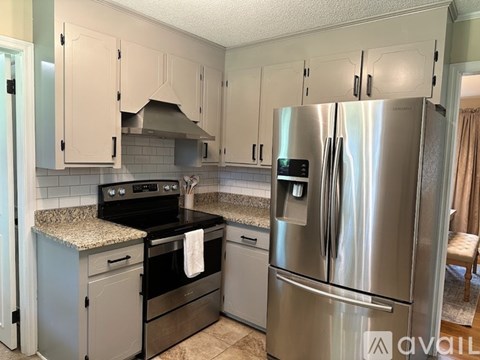 A kitchen with a stainless steel refrigerator and a black stove top oven.