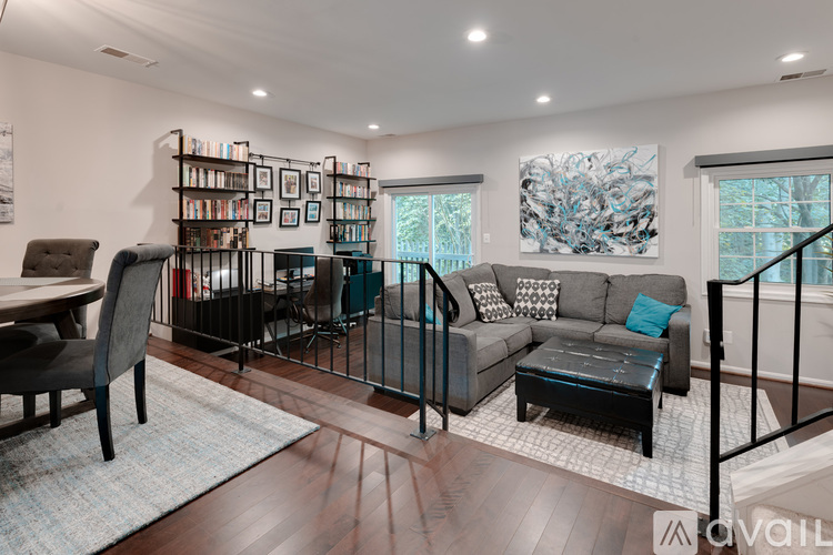 A living room with a grey couch, a black chair, a coffee table, and a bookshelf with books and picture frames.
