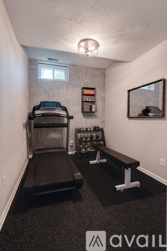 A gym room with a treadmill, weights, and a bench.