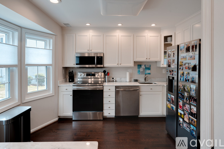 A kitchen with white cabinets and a refrigerator covered in photos.