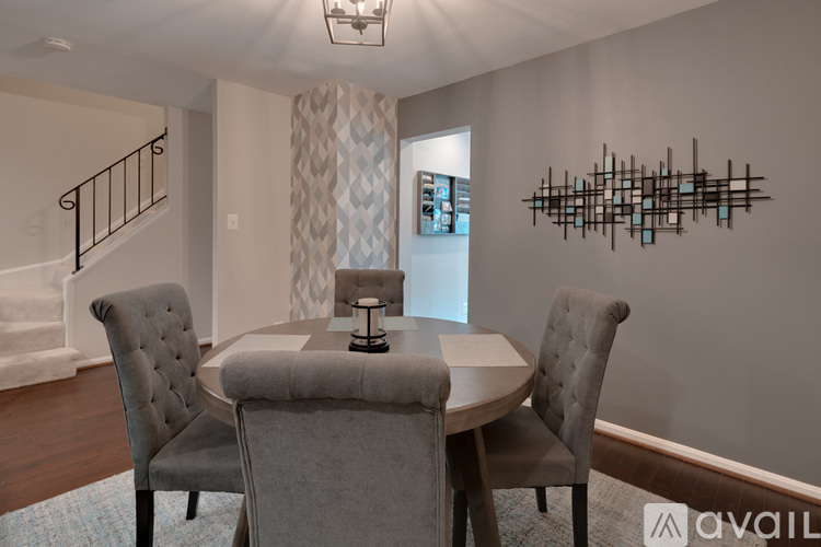 A modern dining room with a round table and grey chairs.