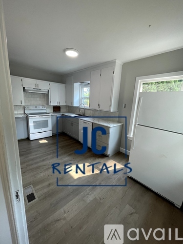 A kitchen with a white fridge and cabinets is for rent.