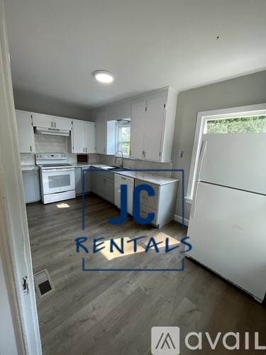 A kitchen with a white fridge and cabinets is for rent.