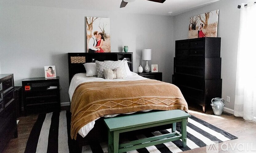 A bedroom with a bed, nightstand, and a green bench.