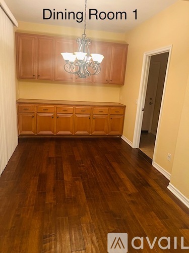 A dining room with wooden floors and a chandelier.