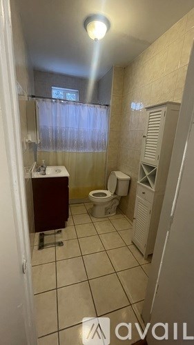 A bathroom with a toilet, sink, and cabinet.