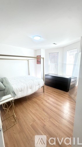 A bedroom with a bed, a chair, and a wardrobe.