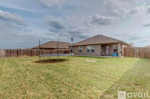 A house with a fence and a trampoline in the yard.