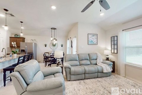 A living room with a grey sofa and a kitchen area in the background.