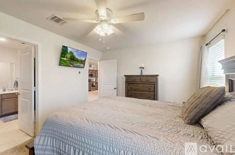 A bedroom with a large bed and a ceiling fan.