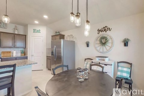 A kitchen with a table and chairs in the foreground and a refrigerator in the background.