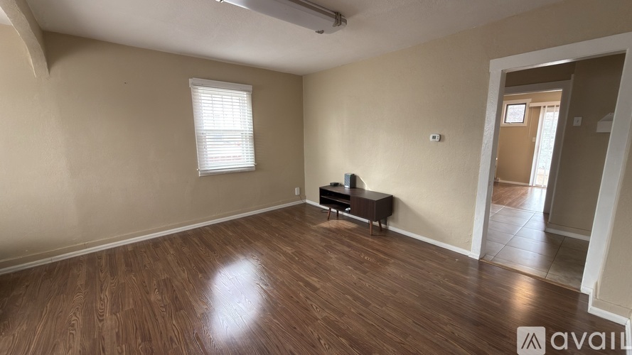 A room with wooden flooring and a window with blinds.