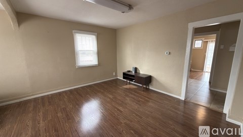 A room with wooden flooring and a window with blinds.