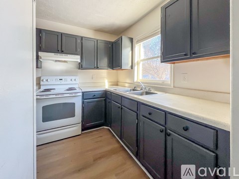 A kitchen with a white stove top oven and black cabinets.