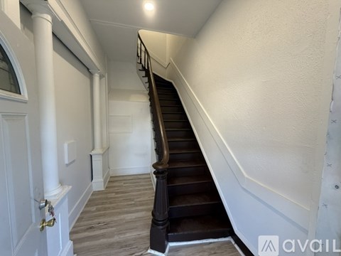 A staircase with a wooden handrail and white walls.